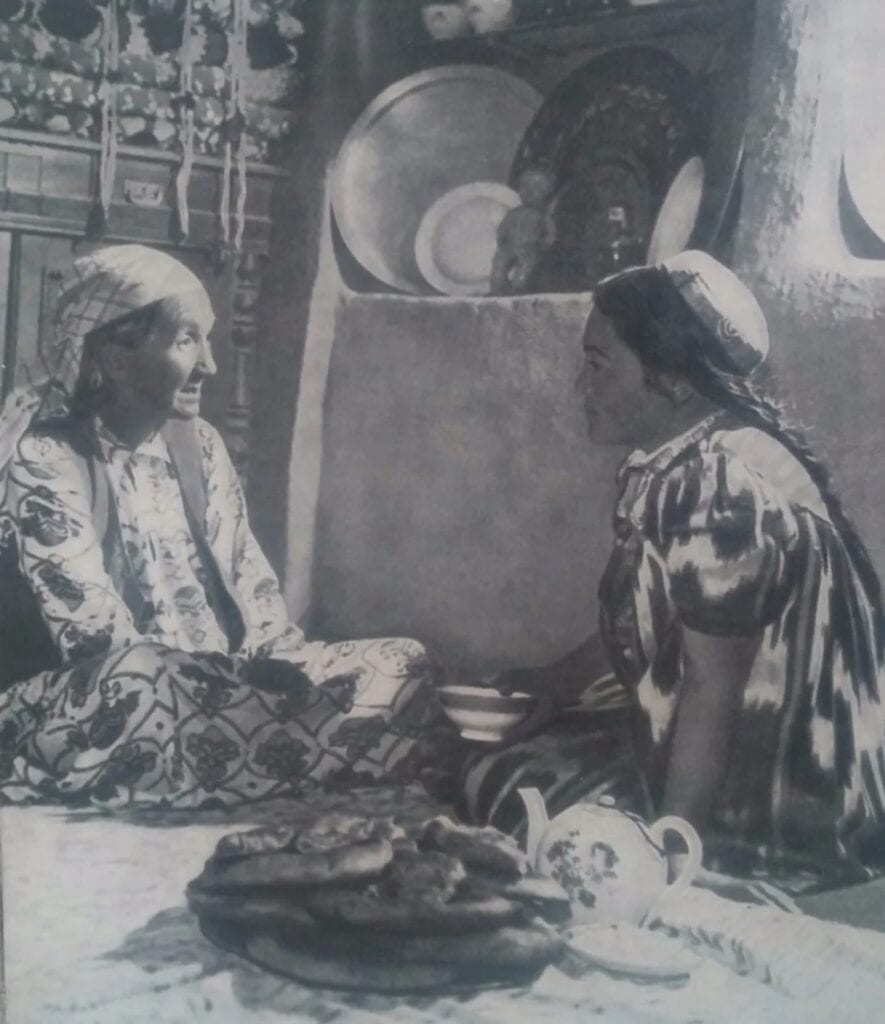 1960 Photograph of two women sitting on a floor mat and drinking tea in a rural area of Uzbekistan